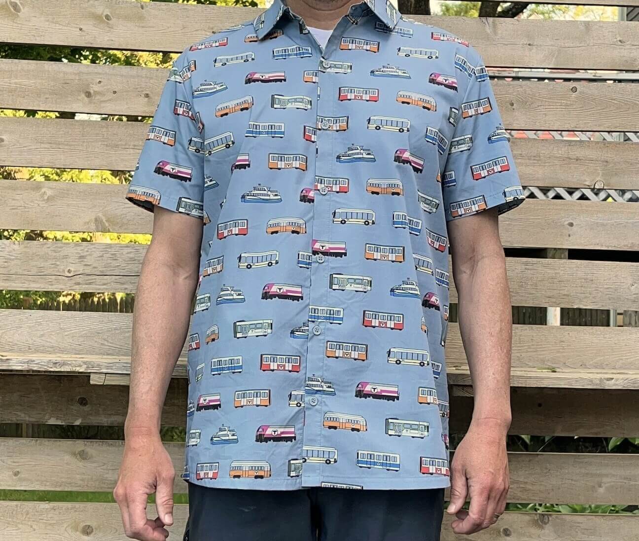 Man wearing light blue button-up short sleeve shirt with fun Boston MBTA vehicle pattern